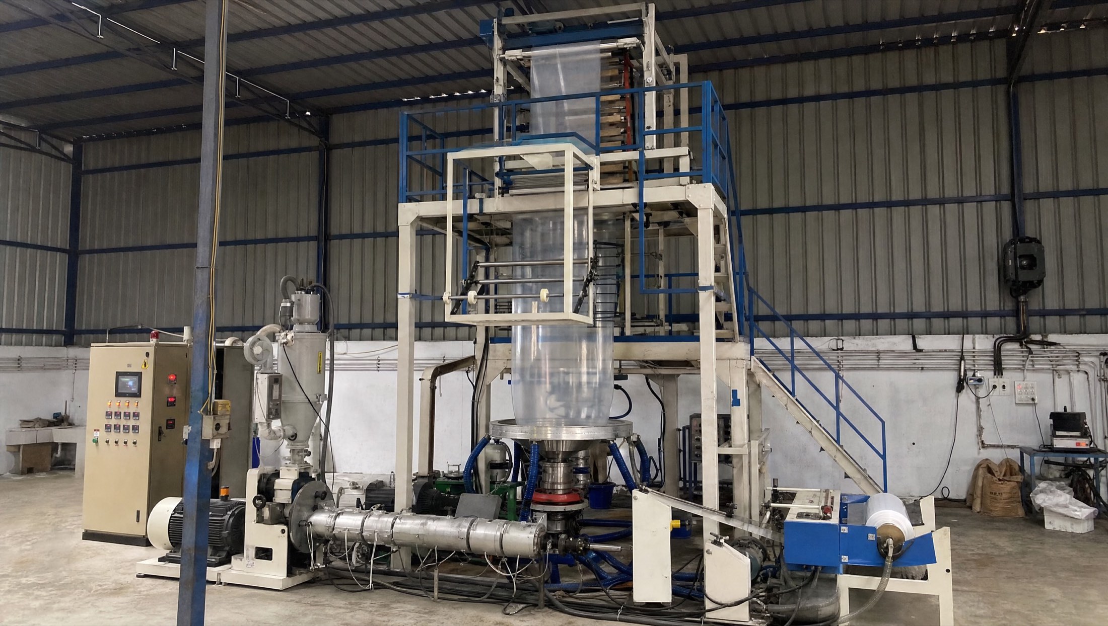Blown film extrusion line — the bubble in its stabilising cage, tower and haul-off, extruder and hopper at floor level